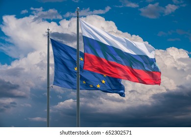 European Union And Russia Flags On Background Of Clouds