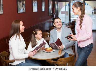european waitress taking table order and smiling at cafe