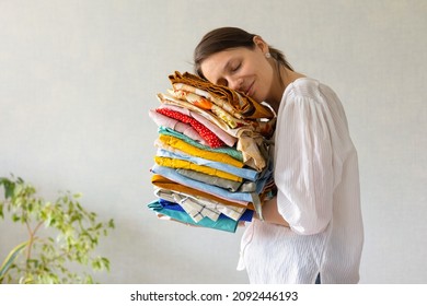 a European woman holds a lot of colored clothes in her hands for washing in the laundry or recycling. children's or adult clothing from the wardrobe. wash and iron your favorite clothes. a woman is a - Shutterstock ID 2092446193