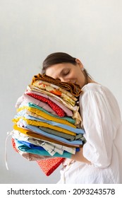 a European woman holds a lot of colored clothes in her hands for washing in the laundry or recycling. children's or adult clothing from the wardrobe. wash and iron your favorite clothes. a woman is a - Shutterstock ID 2093243578