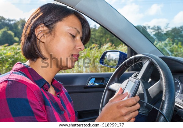 European\
woman operates digital route planner in\
car