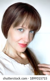 European Woman's Face Portrait Close-up. She Is Light Smiling, Light-blue Eyes, Looking Straight To Cam. Light Brown Hair. Vertical View. White Background.