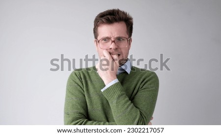 A European young man is nervous and biting his nails.