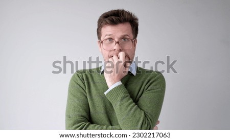 A European young man is nervous and biting his nails.