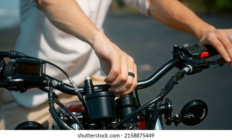 European Young Man's Hands Hold Motorbike Steering Wheel As He Touches Brake Lever Turning Ignition Key