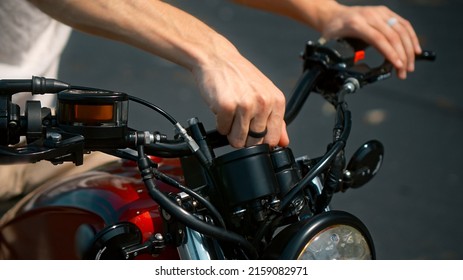 European Young Man's Hands Hold Motorbike Steering Wheel As He Touches Brake Lever Turning Ignition Key