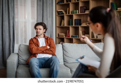 European Young Woman Psychologist Talk With Dissatisfied Guy, Patient Ignoring Doctor Advice In Clinic Interior. Mental Problems, Professional Medical Care, Fight Against Depression, Help And Support