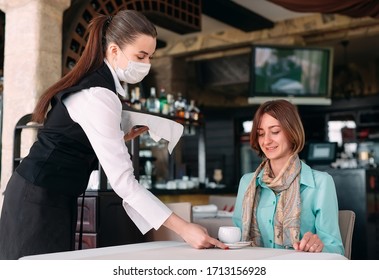 A European-looking Waiter In A Medical Mask Serves Coffee