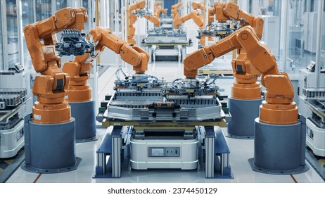 EV Battery Pack Automated Production Line Equipped with Orange Advanced Robot Arms. Row of Robotic Arms inside Bright Plant Assemble Batteries for Automotive Industry. Electric Car Smart Factory - Powered by Shutterstock