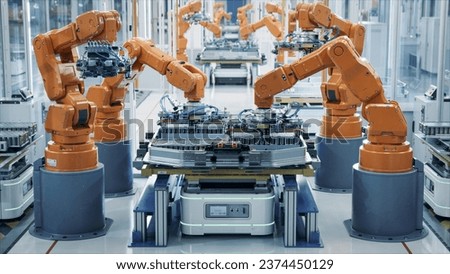EV Battery Pack Automated Production Line Equipped with Orange Advanced Robot Arms. Row of Robotic Arms inside Bright Plant Assemble Batteries for Automotive Industry. Electric Car Smart Factory