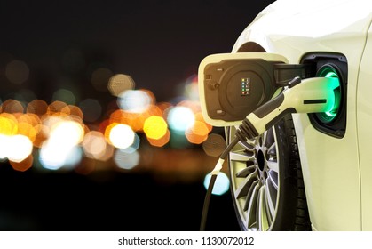 EV Car Or Electric Car At Charging Station With Power Supply Plugged In On Blurred Car Light On A Road Trip At Night.