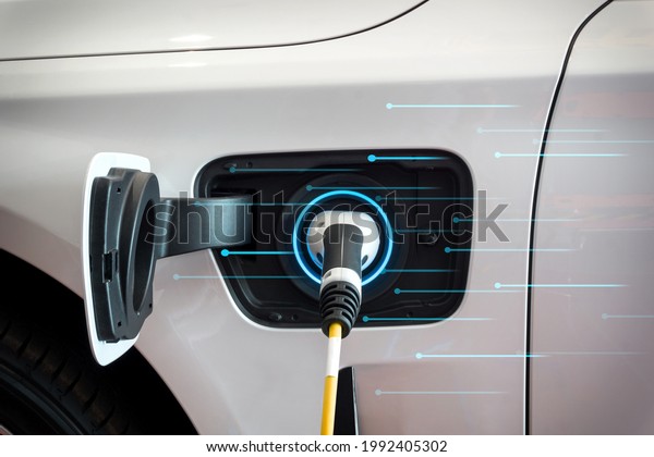 EV Car or Electric car at charging station\
with the power cable supply plugged in with Blue lights background.\
Eco-friendly alternative energy\
concept