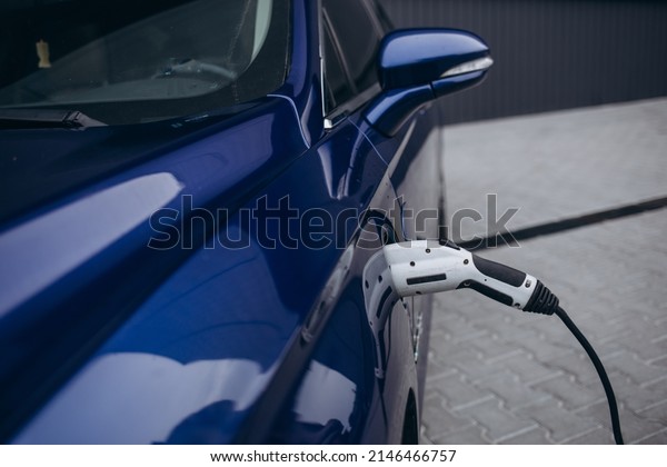EV Car or\
Electric car at charging station with the power cable supply\
plugged in on blurred nature with soft light background.\
Eco-friendly alternative energy\
concept