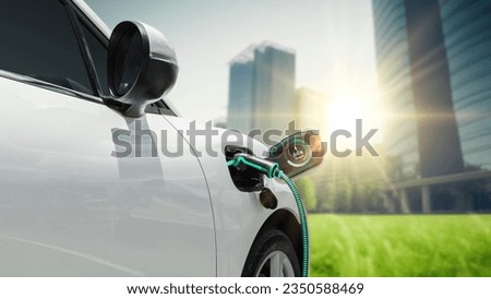EV car plug in with charging station to recharge electricity from EV charger display battery status hologram in green park as futuristic eco lifestyle in city and utilization of clean energy. Peruse