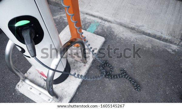 EV charger or electronic vehicle charger that have\
charging cable in plug socket and recharging power to lithium ion\
battery in hybrid automobile which represent future of\
transportation green energy