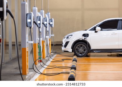 EV charging an electric car. Power supply for electric car charging. Socket for electrical car battery charger. EV car charging station in parking. Nature energy, Clean energy, Green eco concept. - Shutterstock ID 2314812733