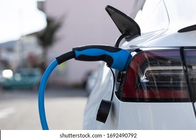 EV Electric Car Pluged Charging At A Recharge Station In The City