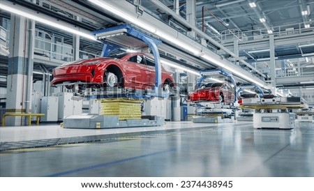 EV Production Line on Advanced Automated Smart Factory. High Performance Electric Car Manufacturing. Car Batteries being Attached to Electric Vehicles on Assembly line. AGV Transport Batteries.