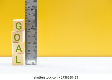 Evaluating goals and the success of business strategic process, business concept : Word GOAL on cubes, measured by a ruler, depicts setting and evaluating a company or employee goals and performance