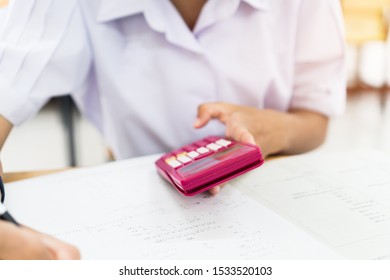 Evaluation or measurement concept. Student using calculator for used making mathematical calculations in exercise taking exam at school or university, taking in assessment paper on education study.