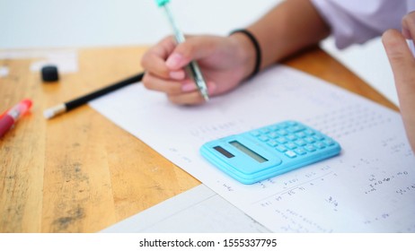Evaluation or measurement concept. Student using calculator for used making mathematical calculations in exercise taking exam at school or university, taking in assessment paper on education study.