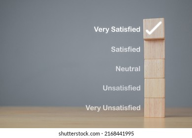 Evaluation And Satisfaction Concept. On Wood Blocks, A Correct Mark Shows Very Satisfied Customers. Copy Space On Grey Background.