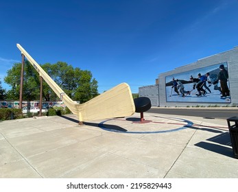 Eveleth, Minnesota -2022: World's Largest Free-Standing Hockey Stick And Puck In Ice Hockey Plaza In Town Nicknamed Hockeytown USA. Big Stick Or The Stick. Mural Of Pond Hockey Or Shinny.