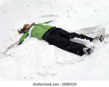 Even Grown Up Girls Like To Make Snow Angels.  This Young Woman Is Wearing Black Pants And Lime Green Jacket.