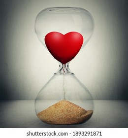 Even love is not eternal concept. Love is temporary conceptual photo manipulation. Closeup of hourglass with heart inside pouring down transforming into sand isolated on gray background.