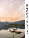 Evening atmosphere at Wolfgangsee lake. Small sailbot moored at port.