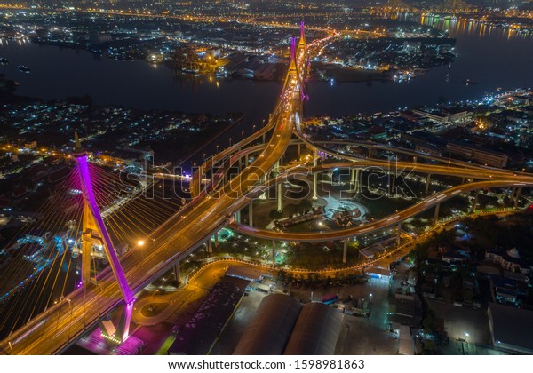 Evening bridge with lights on the bridge over the\
Chao Phraya River. Aerial view of the Bhumibol Adulyadej Suspension\
Bridge over the Chao Phraya River in Bangkok with cars on the\
bridge at the sunset
