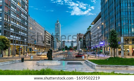 Evening in business part of city Milan located on the Vittor Pisani Street (Via Vittor Pisani) day to night timelapse. Traffic on the road. Light in windows