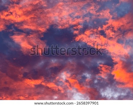Evening cloudscape at twilight, with a scattering of irregular orange clouds illuminated in foreground against dense, shadowy dark violets in background, for motifs of transition and ephemera