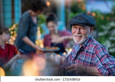 in the evening, dinner with family around a table in the garden, in front of the wooden house. A friendly bearded dad is looking at camera - Powered by Shutterstock