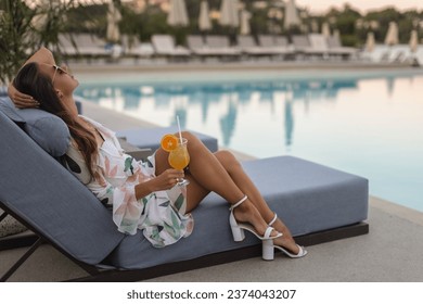 Evening Elegance: Woman with Cocktail Lounging Poolside - Powered by Shutterstock