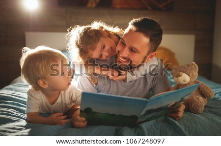 evening family reading. father reads children a book before going to bed 