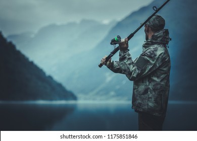 Evening Fly Fishing Time. Caucasian Fisherman with Fishing Rod on the Glacial Lake Shore.