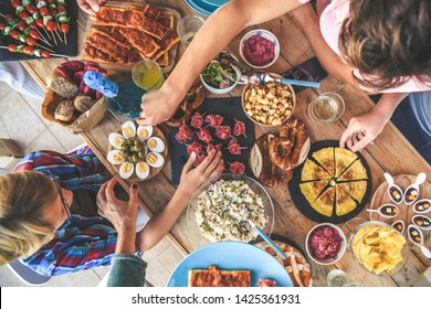 Evening with friend dinner on the terrace enjoying together. Summer aperitif with group of friends Joy and festivities in family View from the top of a table with many foods Happy hands taking viands