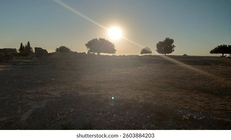 Evening glow casts shadows over ancient ruins under a tranquil sky at sunset