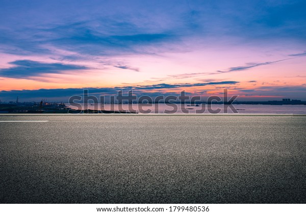  In the evening glow, the wide asphalt pavement\
overlooks the city buildings