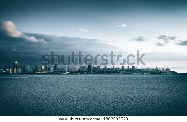 In the evening glow, the wide asphalt pavement\
overlooks the city buildings