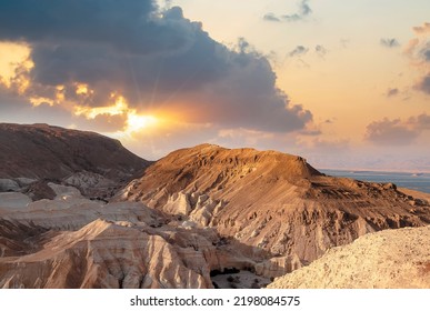 Evening gold sunset sky over mountain Sodom Gomorrah from Negev desert, Israel, Dead sea.  Sunset on a large salt formation mountains range Sodom with fluffy clouds. Sun shining on rocky landscape.  - Powered by Shutterstock