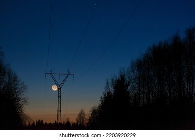 Evening landscape with high-voltage power line, crescent Moon in darkening sky. - Shutterstock ID 2203920229