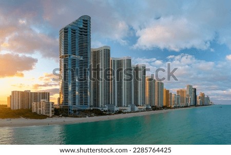 Evening landscape of sandy beachfront in Sunny Isles Beach city with luxurious highrise hotels and condo buildings on Atlantic ocean shore. American tourism infrastructure in southern Florida