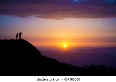 Evening landscape. Silhouettes of two people standing on a rock and looking toward the sun. Sunset in the mountains. Purple light. Summer in the Ukrainian Carpathians. With vignetting effect