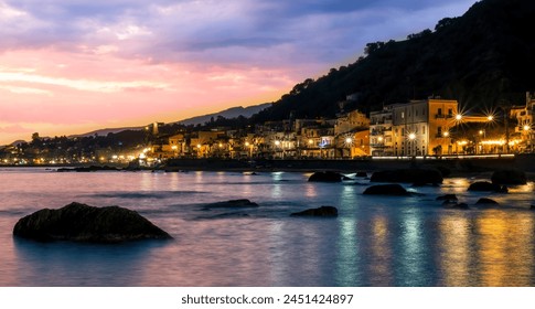 evening or night landscape of evening town coastline in golden lights and sea gulf with calm water and nice reflections with beautisul sunset sky on background - Powered by Shutterstock