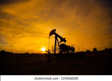 In The Evening. The Oil Pump, Industrial Equipment. Oil Field Site, Oil Pumps Are Running. Rocking Machines For Oil Production In A Private Sector.