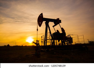 In The Evening, The Outline. The Oil Pump, Industrial Equipment. Field Site, Oil Pumps Are Running. Rocking Machines For Oil Production In A Private Sector.