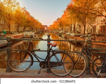 Evening over beautiful Amsterdam canals in autumn. Bicycles parked at the bridges in the foreground 