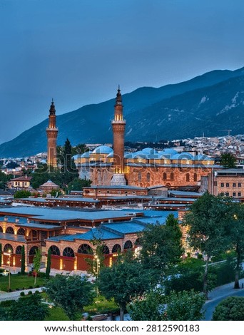 Evening panoramic view of Bursa featuring the historic Grand Mosque (Ulu Cami), traditional city architecture and the slopes of Uludag Mountain under soft twilight light in Bursa, Turkey.